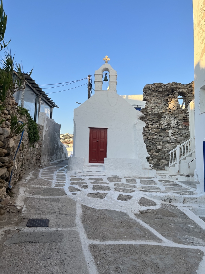 Rue étroite avec une chapelle blanche et des murs de pierre.