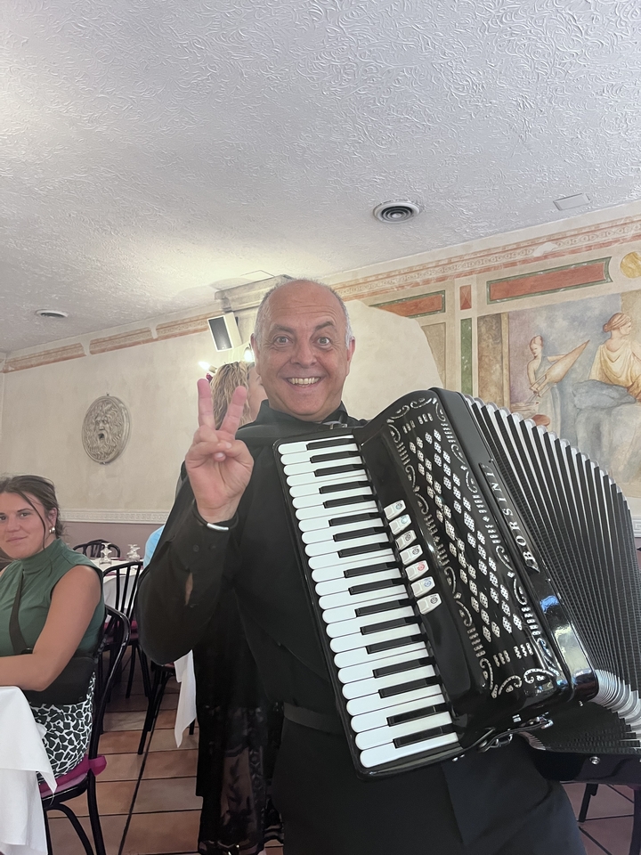 Homme tenant un accordéon et faisant un signe de paix à l'intérieur.