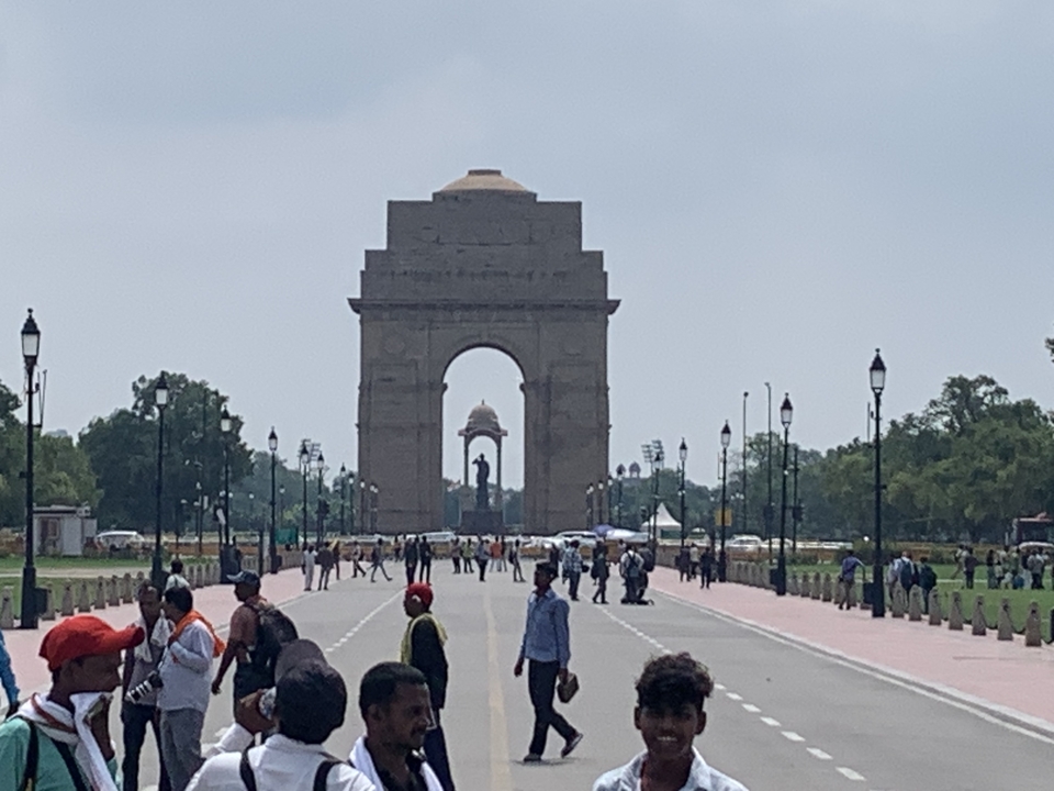 Le monument India Gate à New Delhi avec des touristes au premier plan.