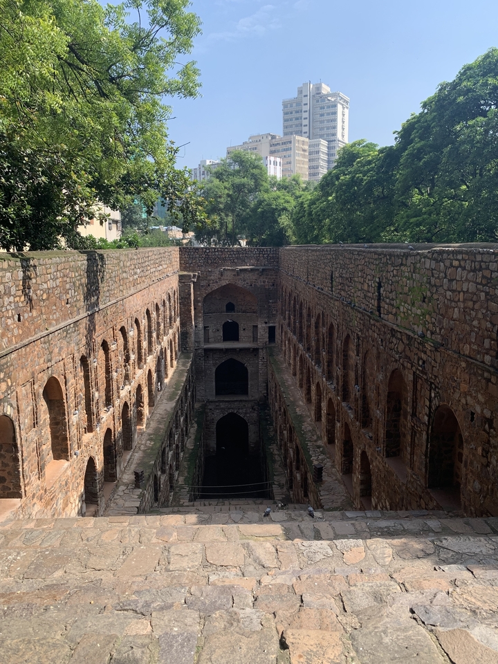 Puits à degrés avec arches en pierre et eau verte.