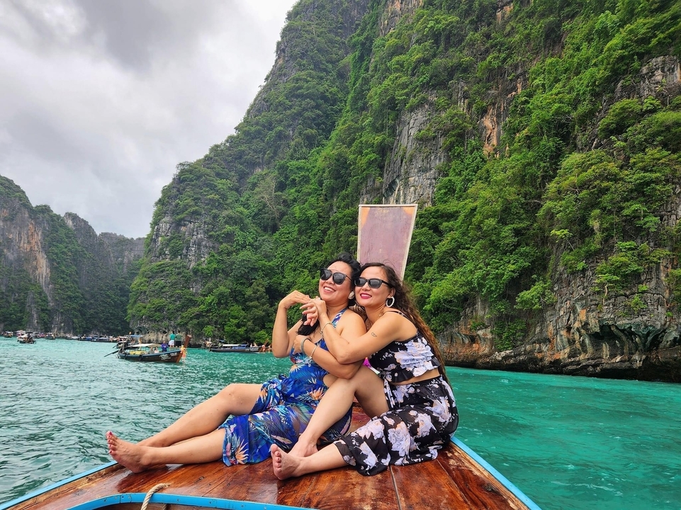 Deux femmes sur un bateau dans des eaux turquoise avec des falaises calcaires.