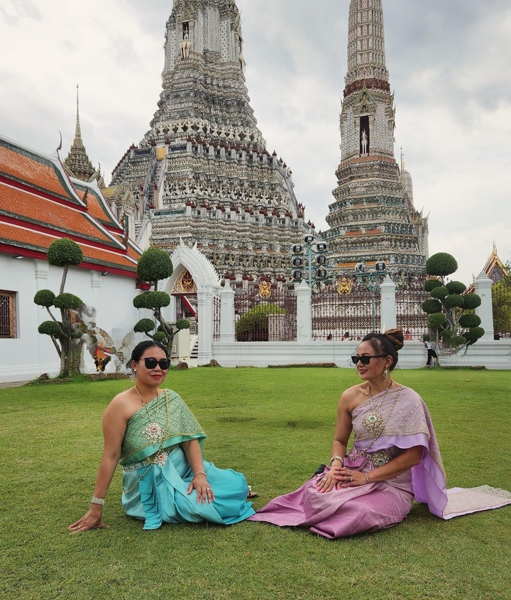 Deux femmes en tenue traditionnelle devant le temple Wat Arun.