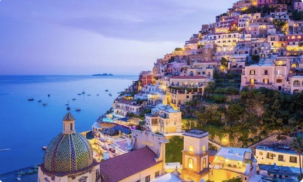 Vue panoramique de Positano au crépuscule avec des bâtiments illuminés.