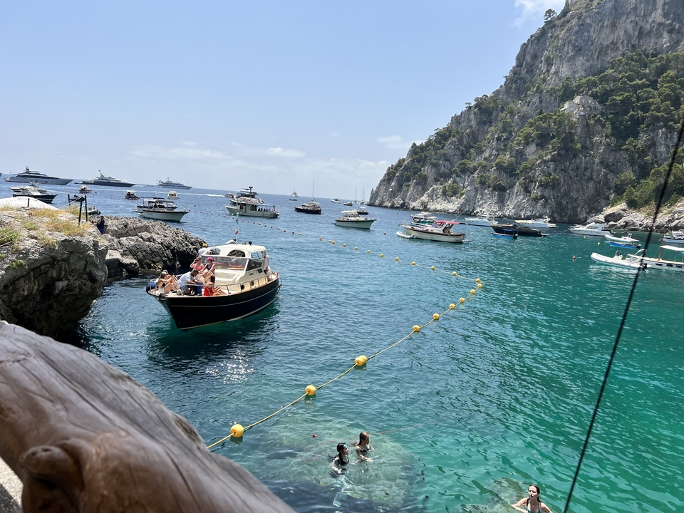 Plusieurs bateaux sur une eau bleue claire avec des falaises rocheuses en arrière-plan.