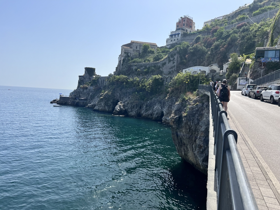 Route côtière avec des falaises escarpées et une personne marchant le long du sentier.