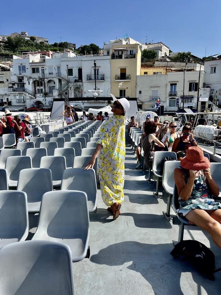 Personne en robe posant sur un bateau avec d'autres passagers.