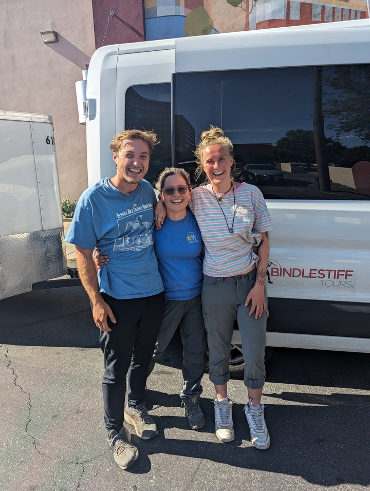 Un groupe de personnes souriantes qui posent devant un van de tourisme.