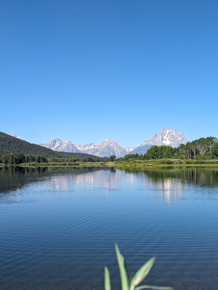 Un lac avec des montagnes se reflétant à sa surface et des gens à proximité.