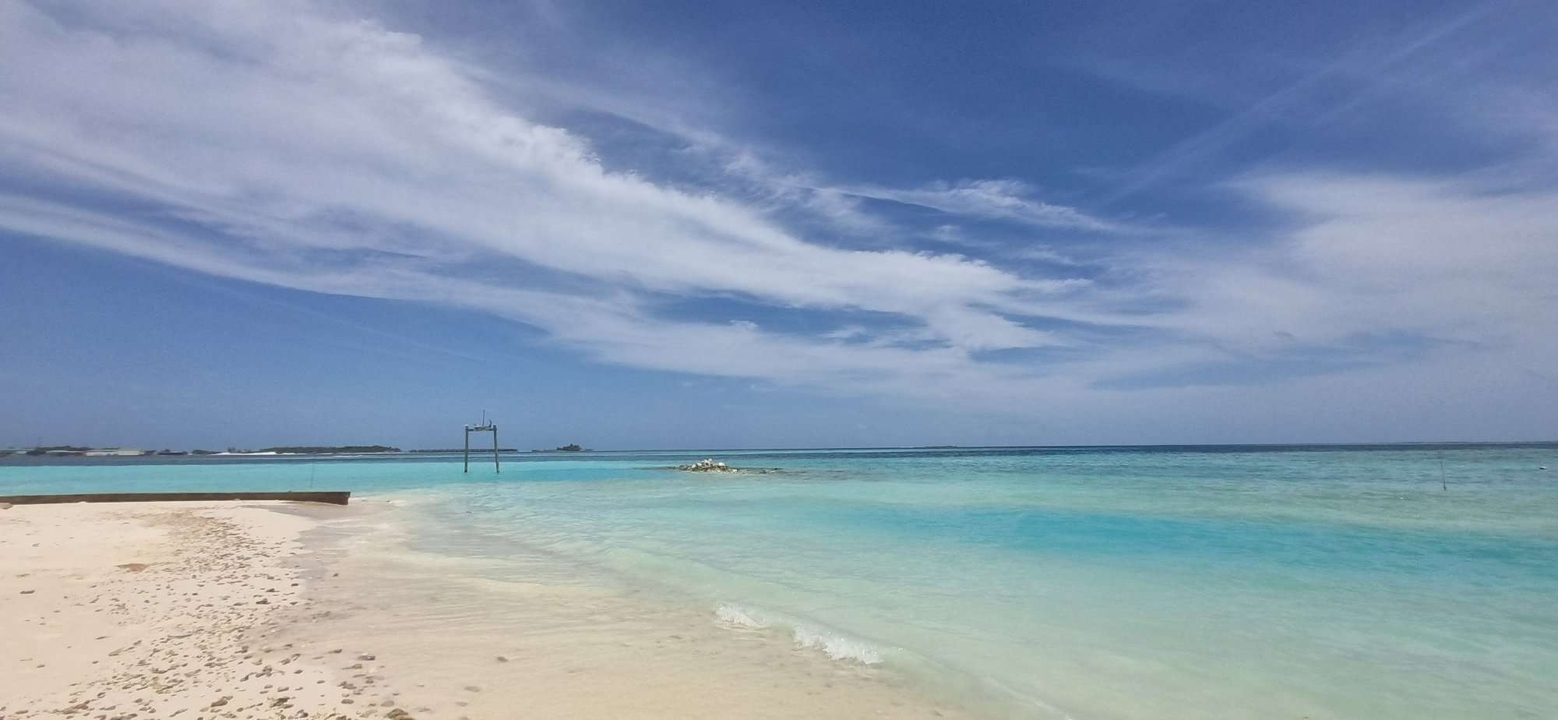 Une vue d'une plage sereine avec une eau turquoise et un ciel bleu.