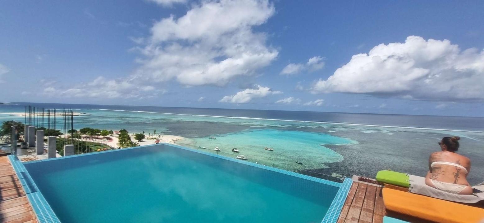 Piscine à débordement surplombant une plage aux eaux tropicales.