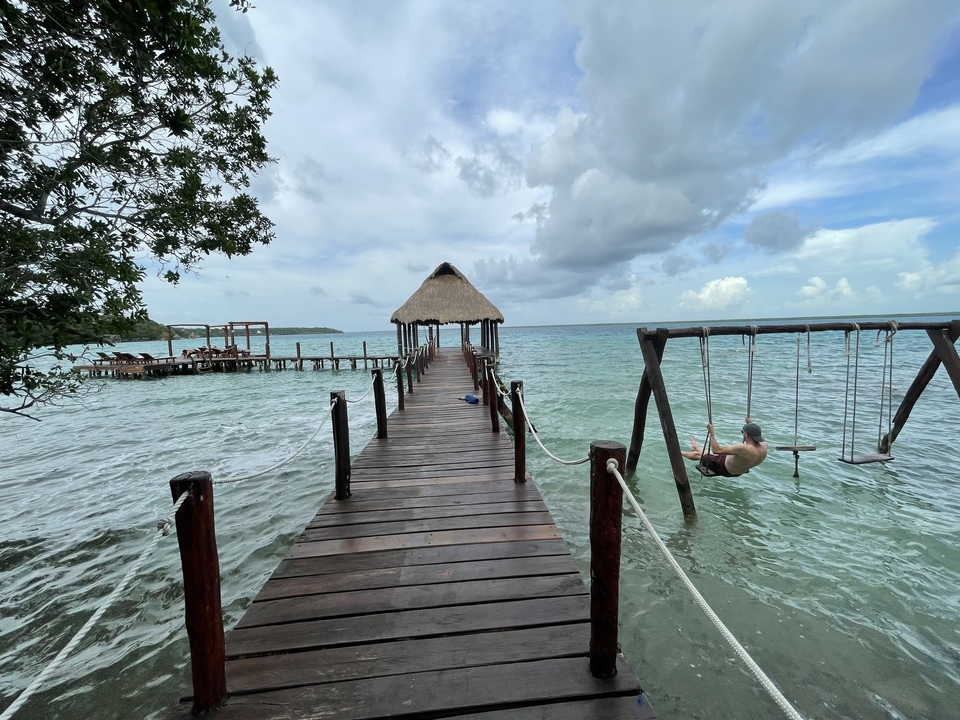 Jetée en bois menant à une cabane sur l'océan, balançoire à proximité.