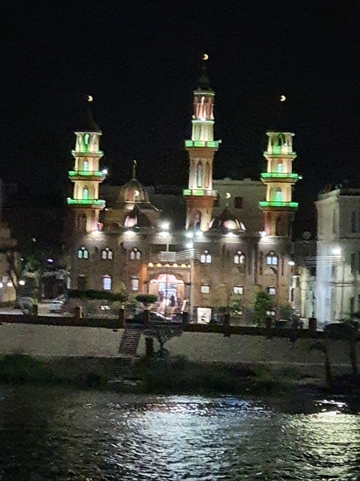 Vue nocturne d'une mosquée illuminée avec des lumières vertes.