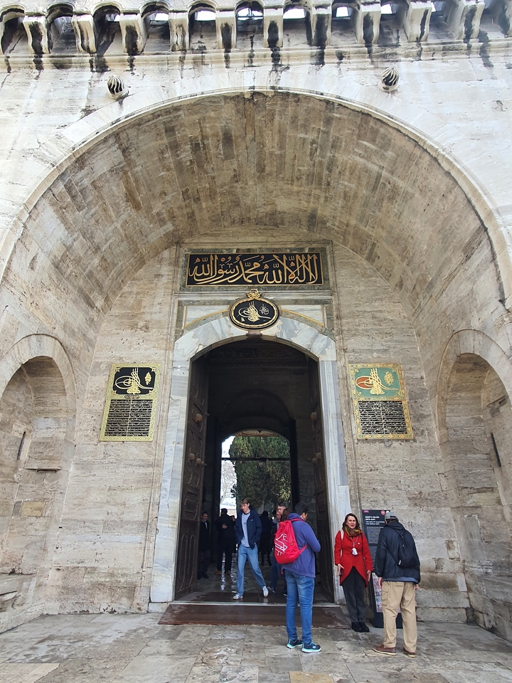 Porte historique en pierre avec calligraphie arabe.