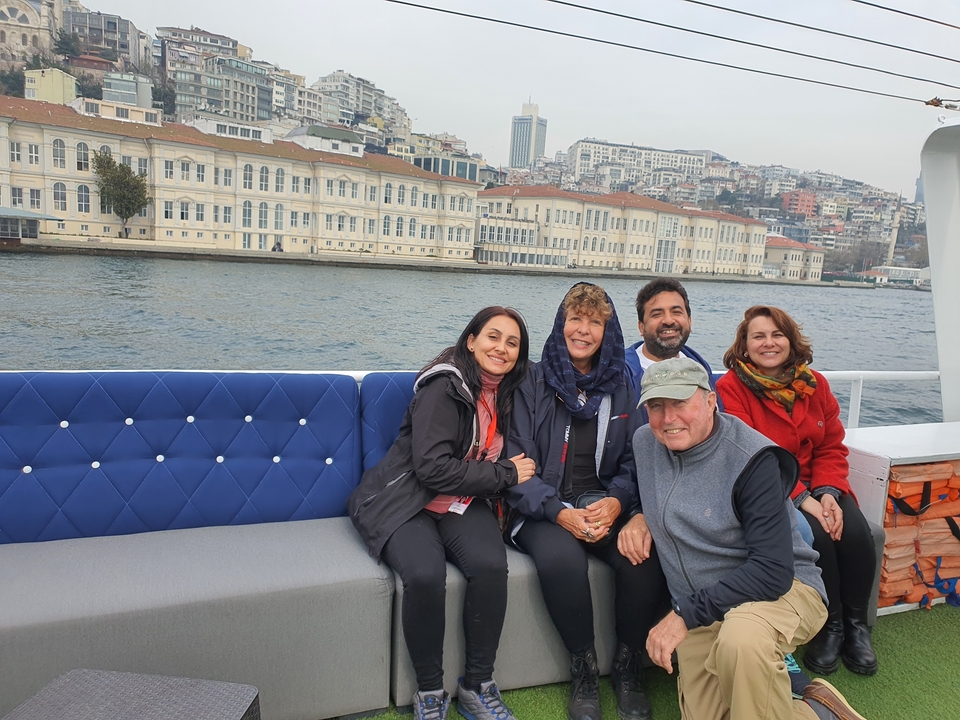 Groupe de personnes sur un bateau avec un paysage urbain en arrière-plan.