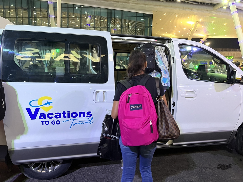 Group of people with luggage boarding a travel van.