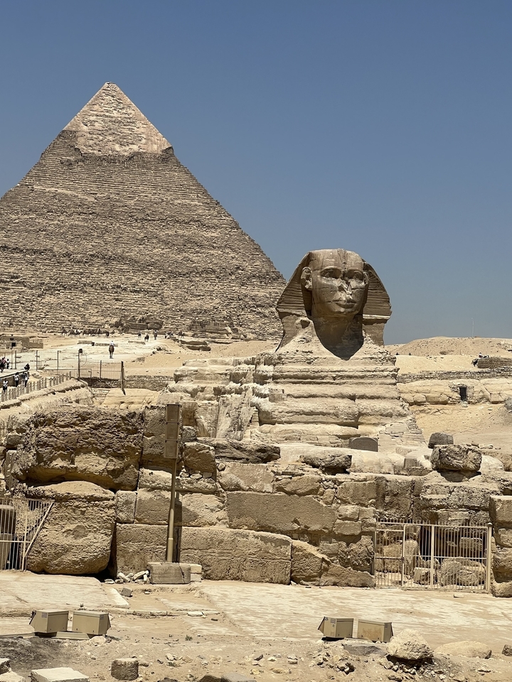 The Sphinx and pyramids in a desert setting with tourists visible.