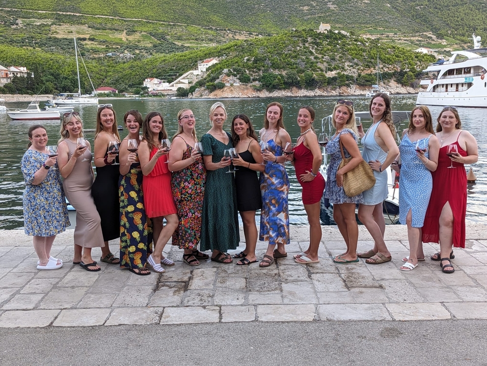 Un groupe de femmes posant avec des boissons dans un lieu en bord de mer.