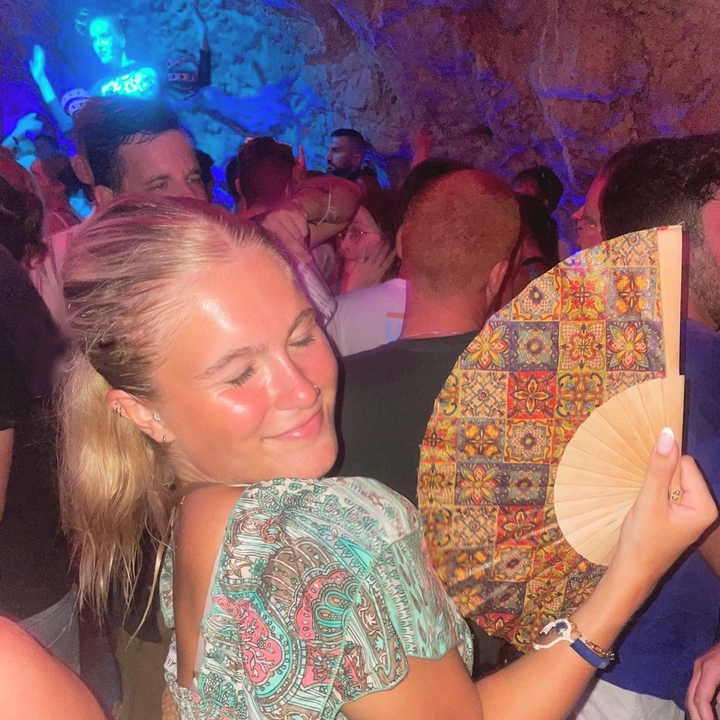 Personne profitant d'une fête nocturne tenant un éventail décoratif.