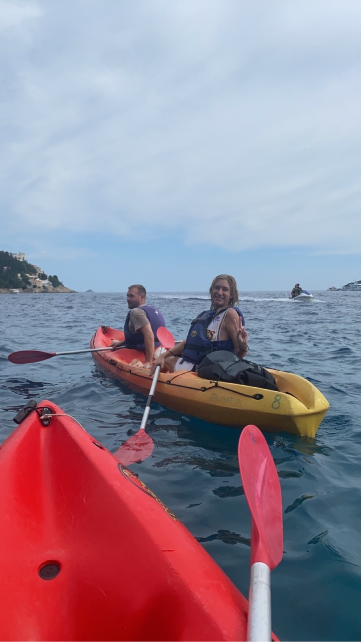 Deux personnes faisant du kayak sur une mer calme avec des jet-skis en arrière-plan.