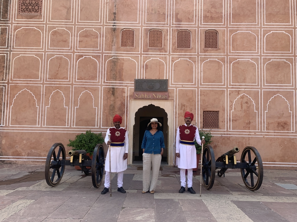 Two guards and a visitor standing in front of a historical building entrance.