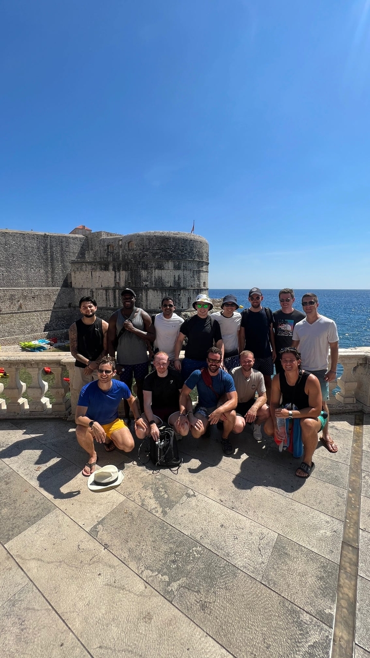 Photo de groupe devant les remparts antiques au bord de la mer.