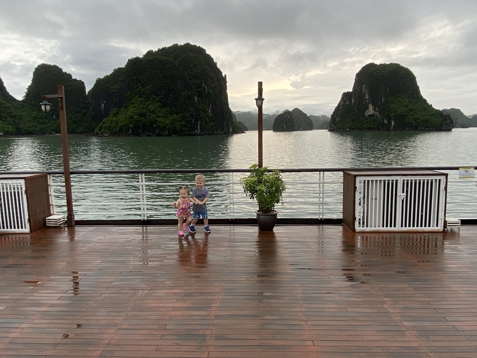 Deux enfants sur le pont d'un bateau avec des îles calcaires en arrière-plan.