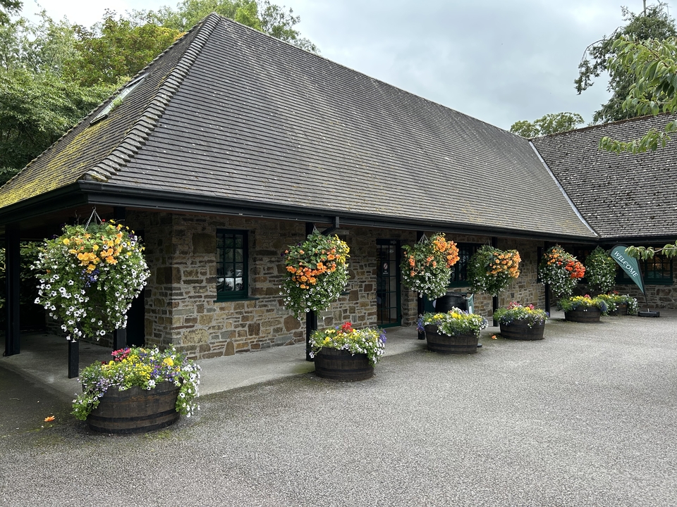 Bâtiment en pierre avec des fleurs colorées et des tonneaux