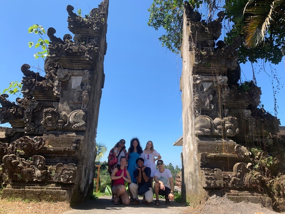 Groupe de touristes debout entre des structures de portails balinais traditionnels.