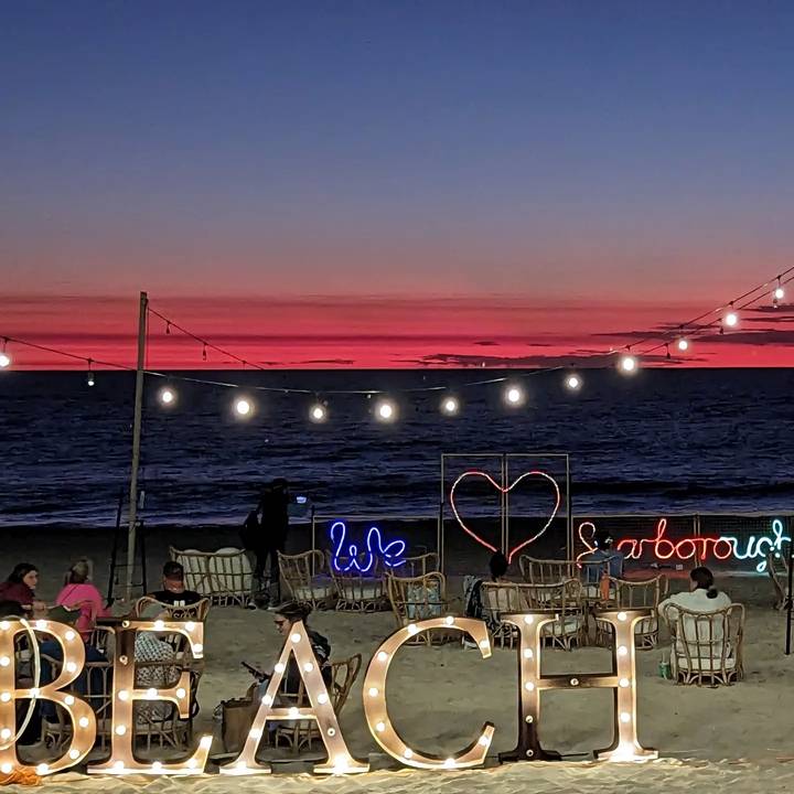 Coucher de soleil sur une plage avec des éclairages décoratifs et des aménagements de sièges.