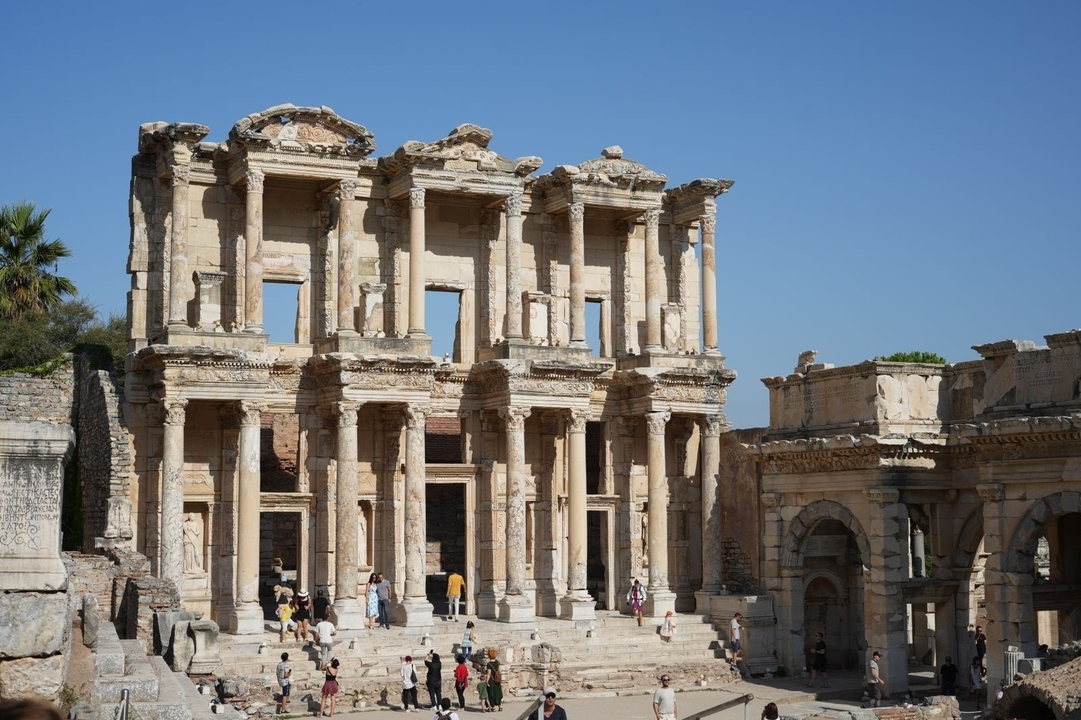 Ruines d'une ancienne bibliothèque avec des sculptures détaillées et des colonnes.