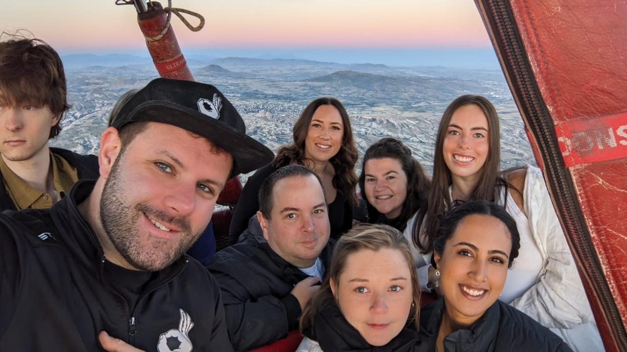 Groupe de personnes souriantes dans une montgolfière en vol.