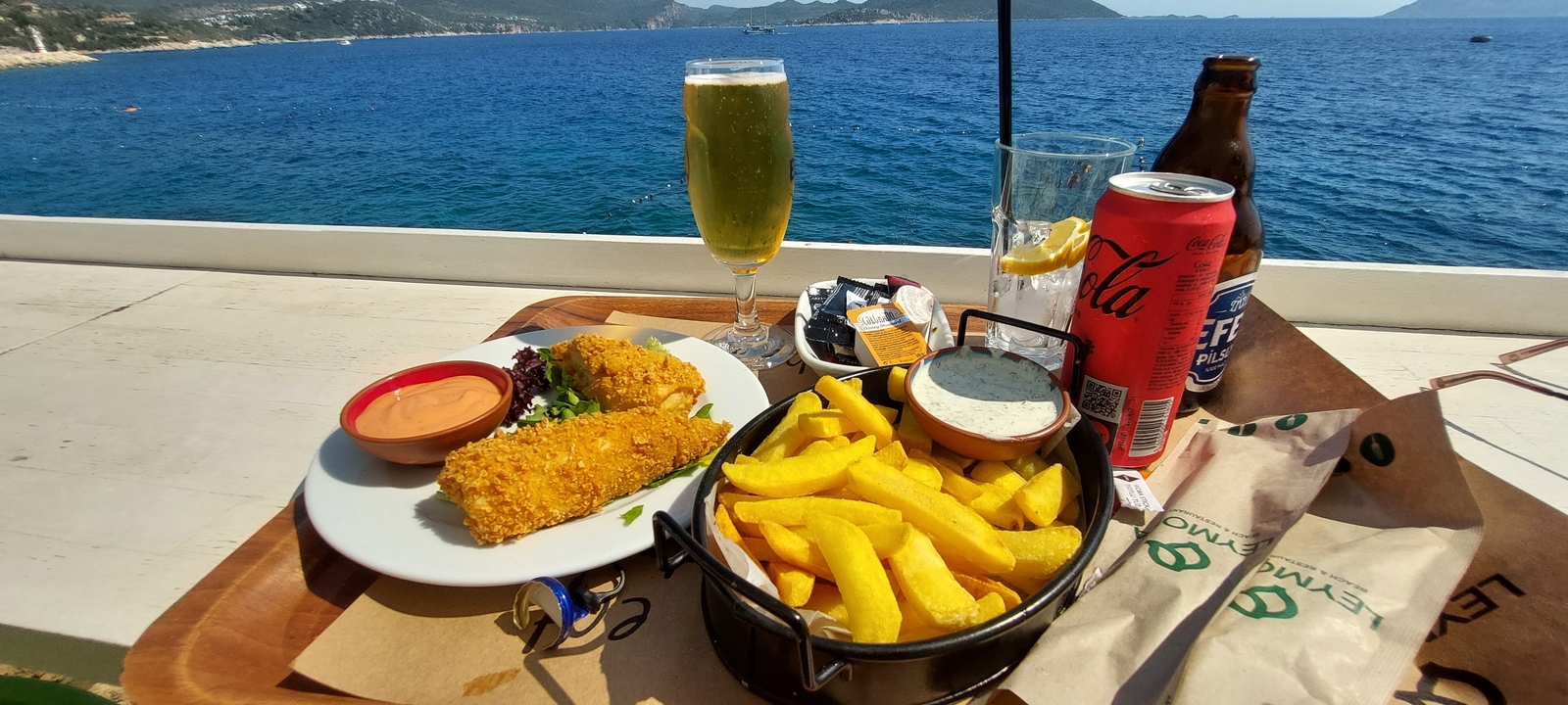 Une table avec un repas de fish and chips avec vue sur mer.