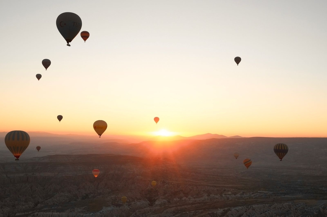 Montgolfières dans le ciel au lever du soleil au-dessus d'un paysage pittoresque.