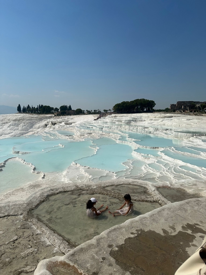 Terrasses de travertin blanc remplies d'eau turquoise.