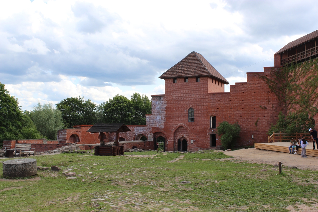 Ruines de château médiéval avec des gens autour.