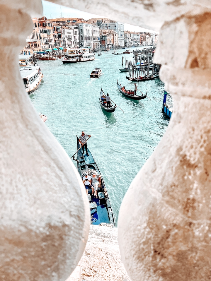 Gondoles sur un canal vénitien vues à travers une balustrade en pierre.