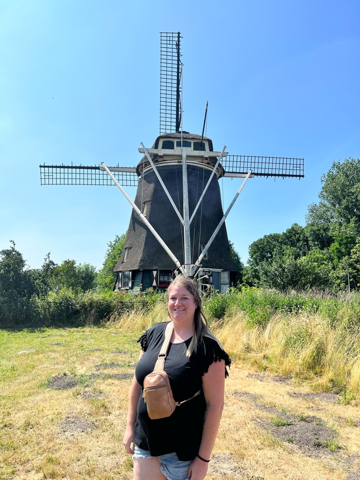 Femme posant devant un moulin à vent traditionnel.