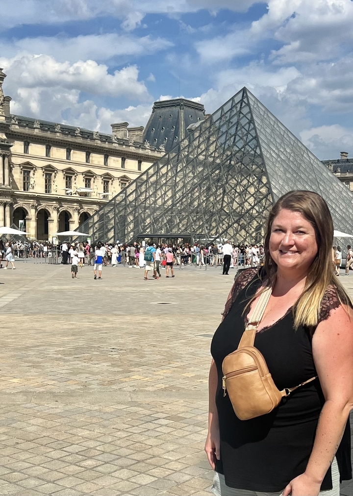 Femme qui pose devant la Pyramide du Louvre.