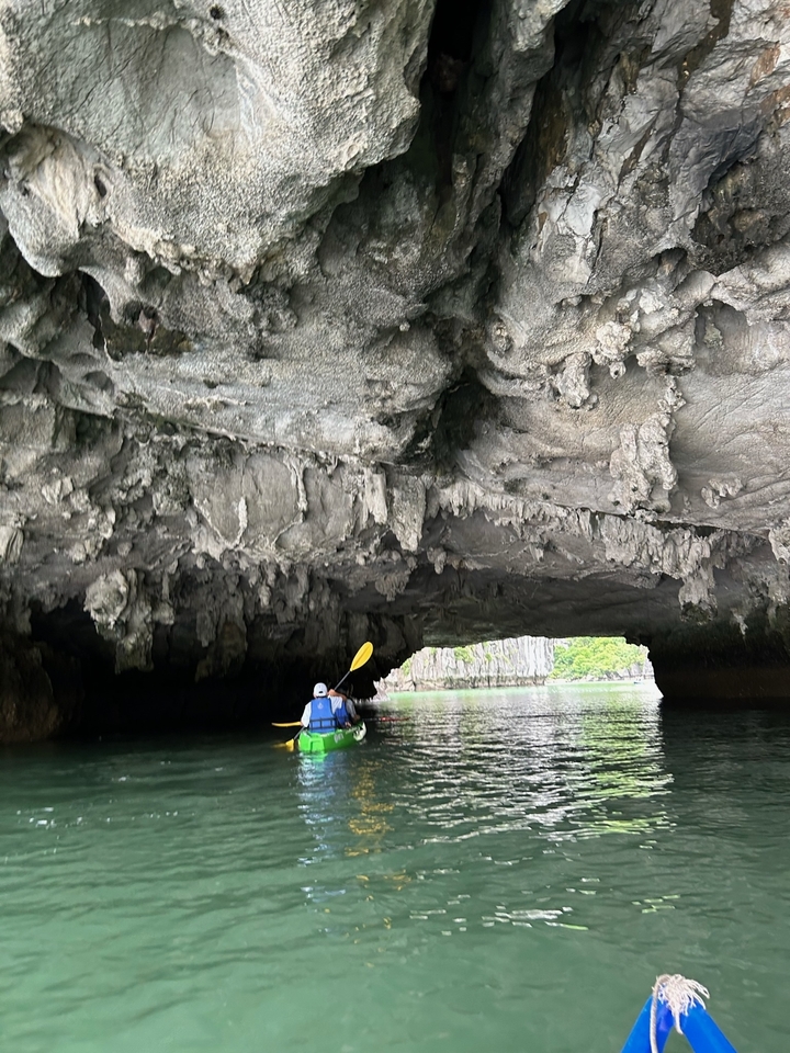 Des gens faisant du kayak sous une arche rocheuse.