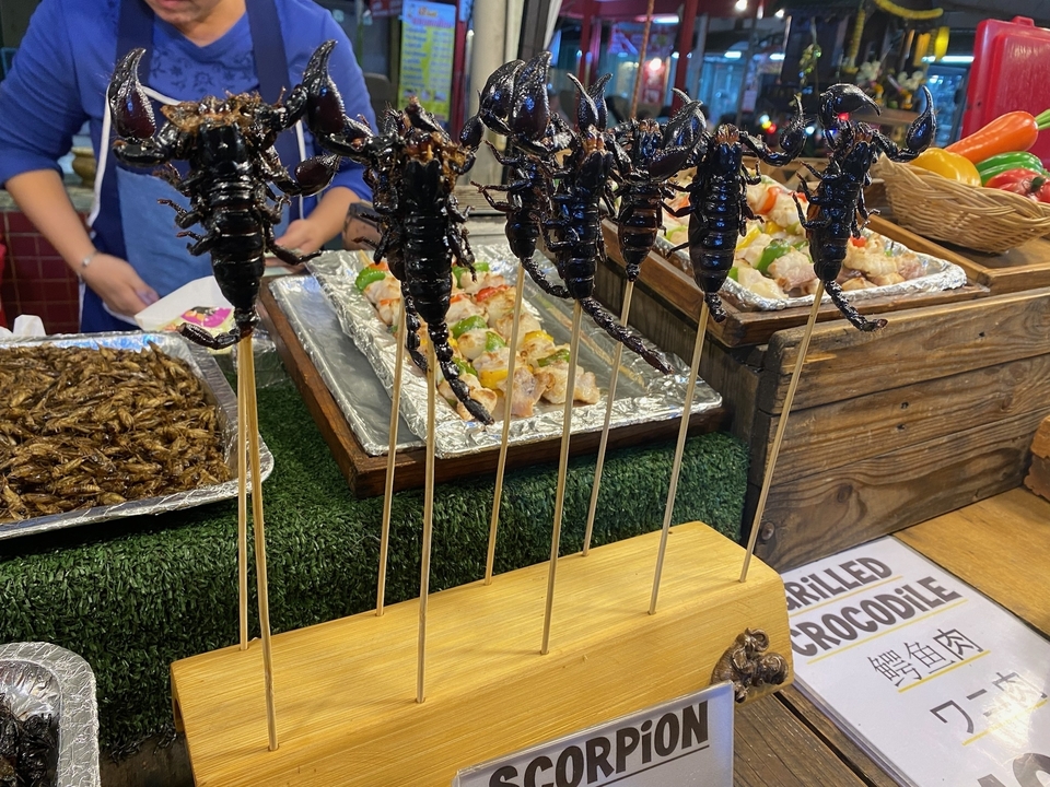 Stand de nourriture exotique avec des brochettes incluant des scorpions.