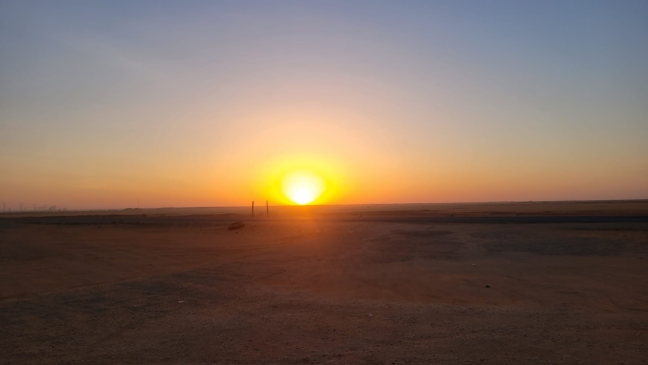 Sunset view in the desert with the sun setting over the horizon.