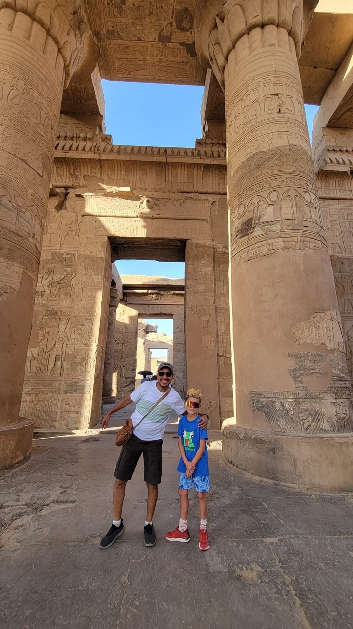 People posing in front of ancient Egyptian ruins with hieroglyphics.