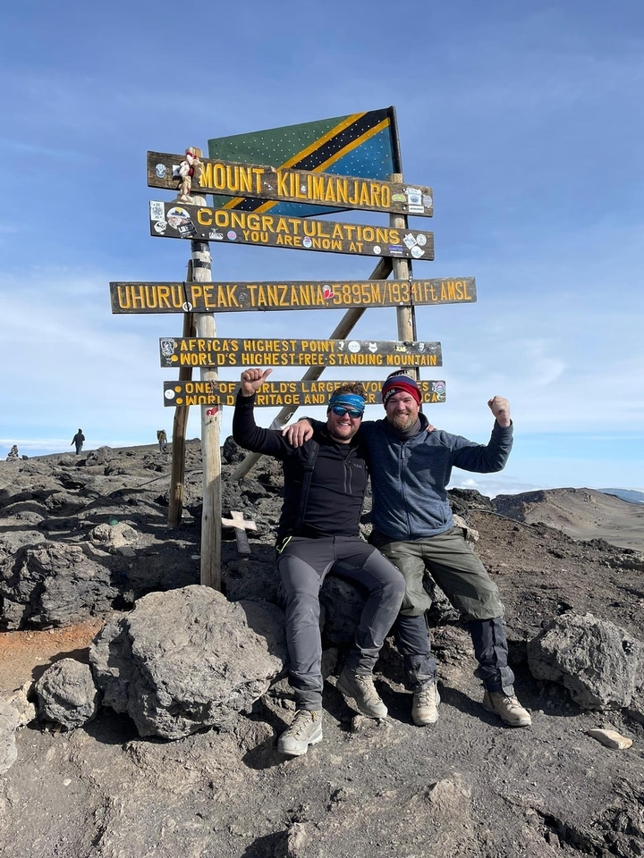 Deux randonneurs posant avec un panneau au sommet Uhuru.