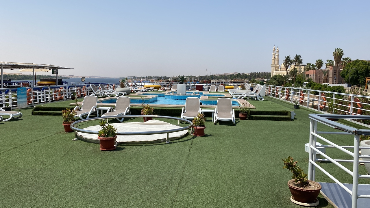 Ein Luxus-Kreuzfahrtdeck mit Sonnenliegen und einem Pool mit Blick auf den Fluss.