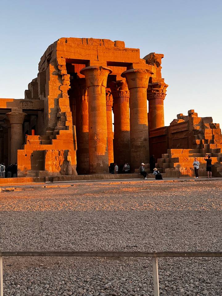 Ruines d'un temple antique avec des colonnes sous un éclairage chaud de coucher de soleil.