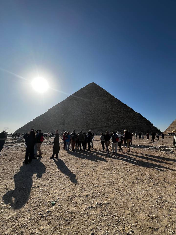 Des touristes se sont rassemblés au pied d'une pyramide.