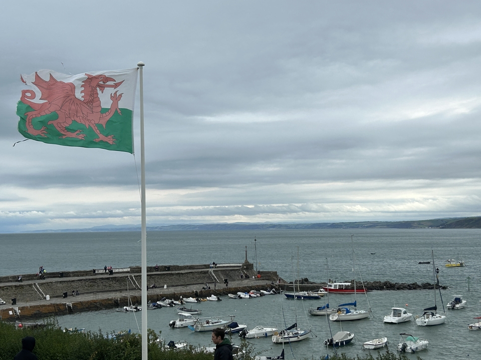 Drapeau gallois flottant près d'un port avec des bateaux.