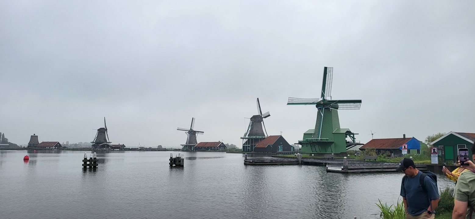 Moulins à vent au bord de l'eau par une journée nuageuse.