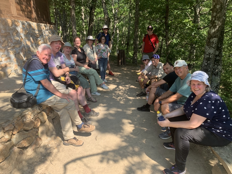 Groupe de personnes assises sur un banc de pierre dans une forêt.