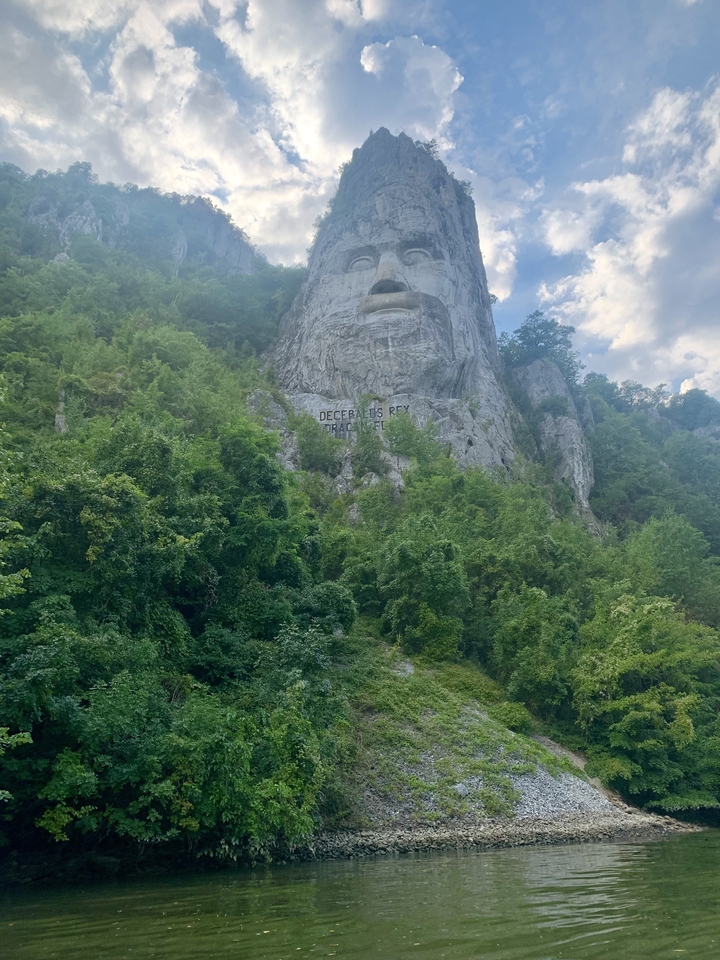 Colline rocheuse avec feuillage et visage sculpté de Décébale.